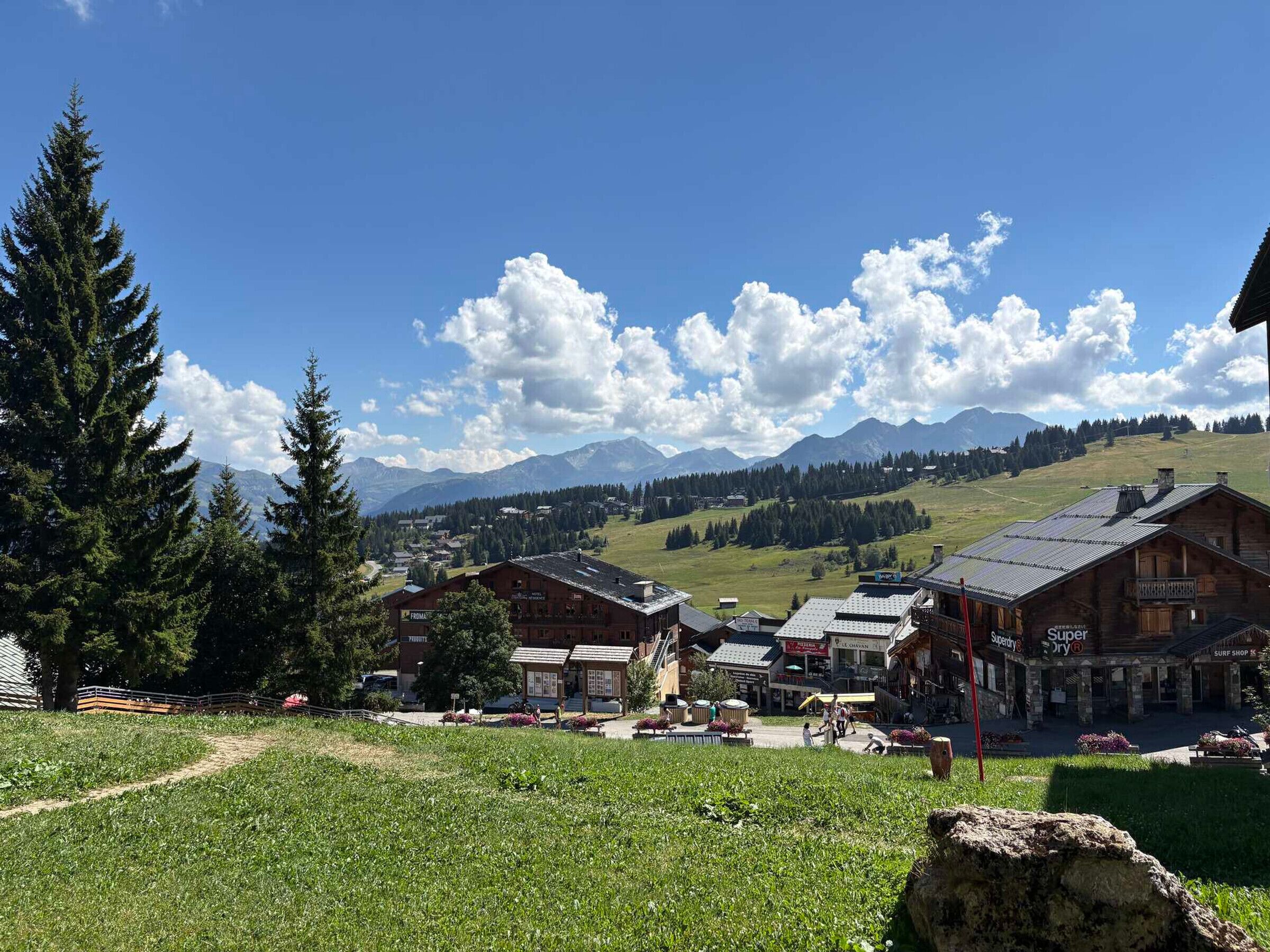 Un pueblo de montaña con edificios tradicionales de madera, cielo despejado y vistas a montañas distantes.