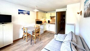 A compact living space with a kitchenette, a dining area, and a sofa. - Studio for 4 people with garage, near village and lifts (La Clusaz)