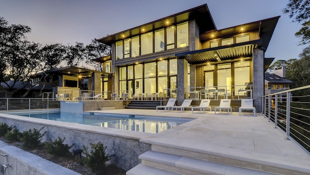 Et moderne hus i to etager med swimmingpool, udendørs møbler og en godt oplyst terrasse.