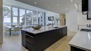 Et moderne køkken med en stor ø, masser af naturligt lys og havudsigt.