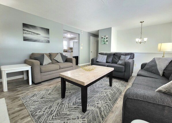 A modern living room with two sofas, a coffee table, and a small white table.