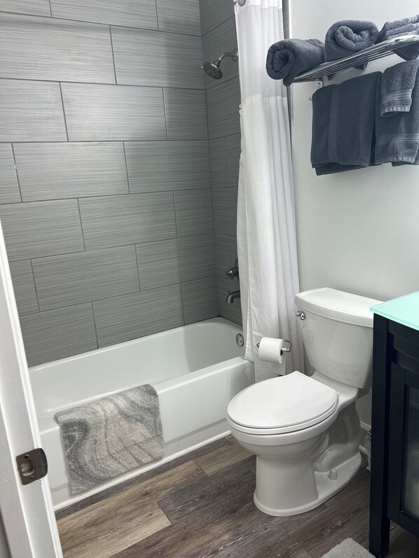 A bathroom with a shower, toilet, and a towel rack.