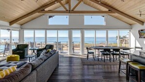 Ruime kamer met een hoge plafond, grote ramen en uitzicht op het strand.