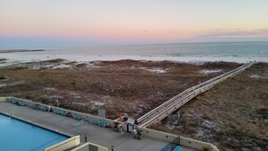Ein Strand mit einer Holzpromenade, einem Poolbereich mit Liegestühlen und Blick auf den Ozean.