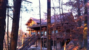 A cabin with a staircase leading to a deck, surrounded by trees.