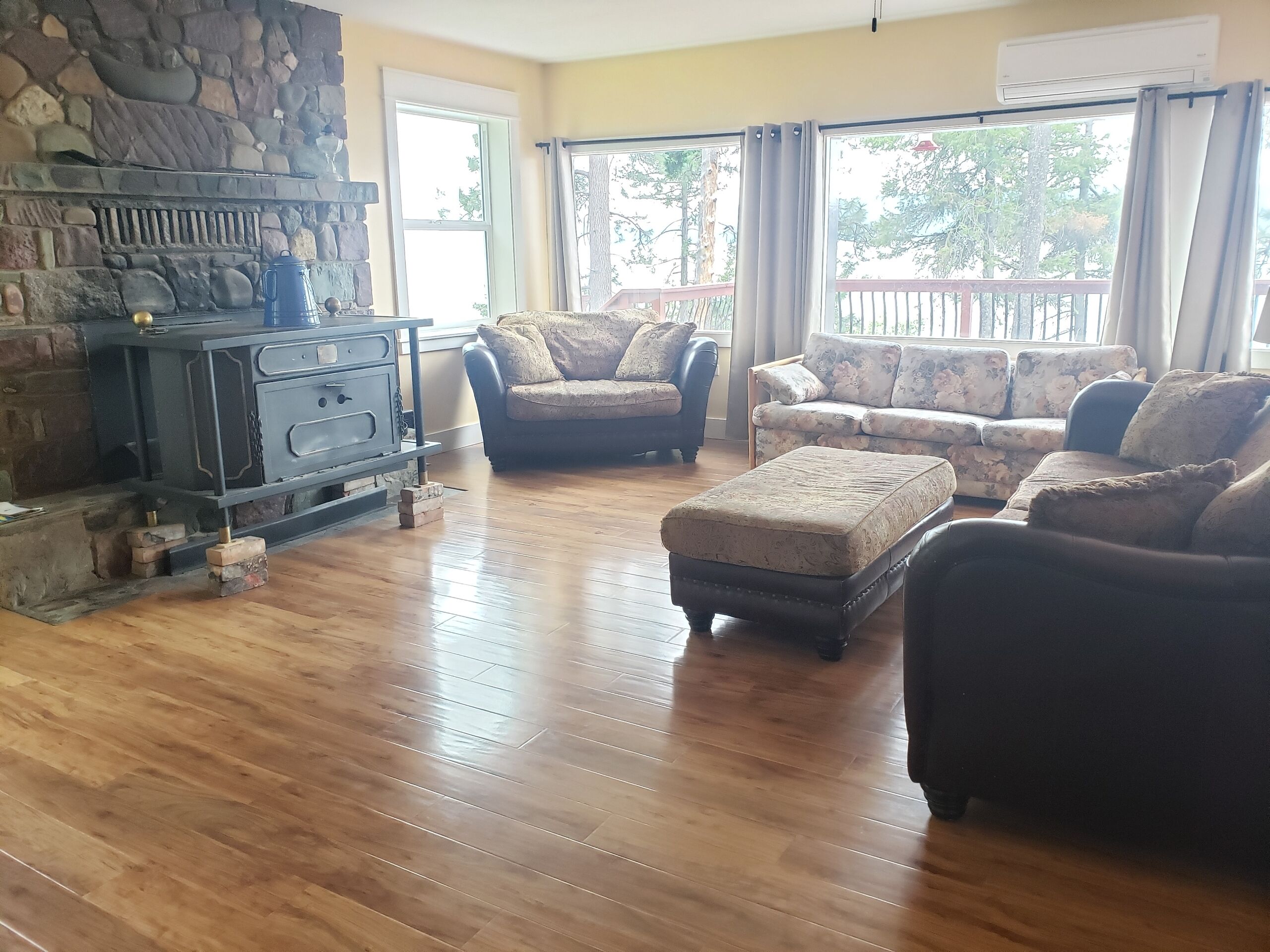 A living room with a stone fireplace, two sofas, and a wooden floor.