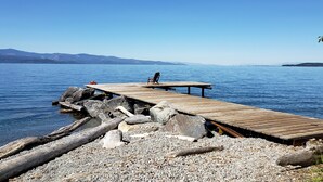 Une jetée en bois s’avançant dans une étendue d’eau calme, avec une chaise et une table qui s’y trouvent.