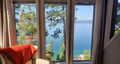Peaceful home enveloped in a quiet, scenic landscape adjacent to a rocky beach.