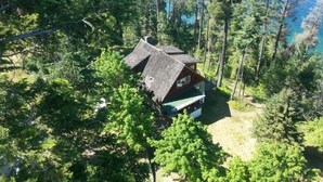 Une cabane entourée d’une forêt dense, offrant une vue dégagée sur un lac.