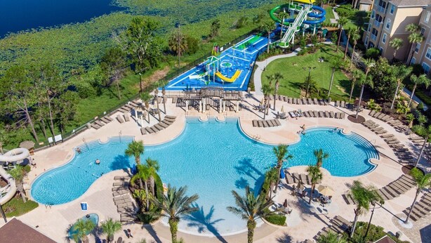 A resort with a large pool, a water park, and a well-maintained lawn area.