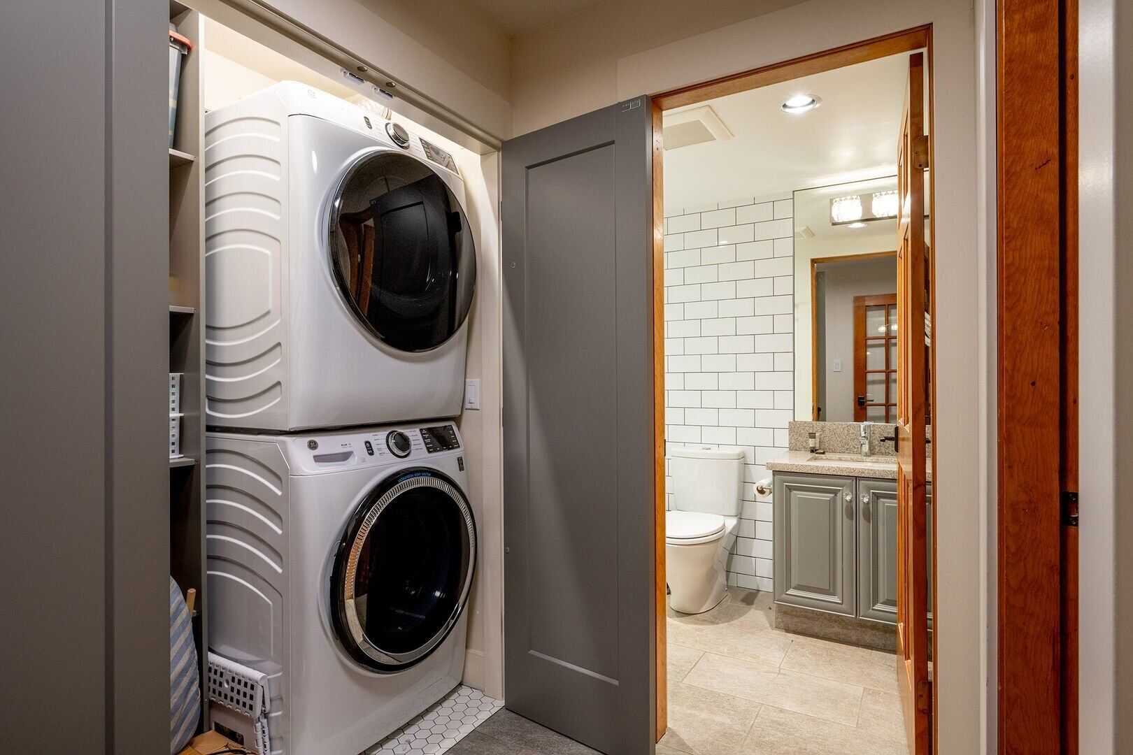 Een praktische wasruimte met een voorlader wasmachine en droger, een toilet en een klein wastafelgedeelte.