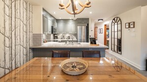 Une cuisine moderne avec des meubles gris, un îlot central et un lustre.