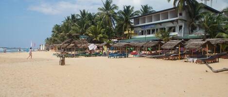 Rannalla, aurinkotuoleja, aurinkovarjoja, rantapyyhkeitä