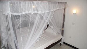 A bed with a white canopy and a wall-mounted light fixture. - Hotel Ritas & Beach Restaurant (Hikkaduwa)