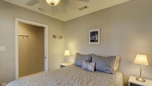 Un dormitorio con una cama, dos lámparas de noche, un cuadro enmarcado en la pared y una puerta con la leyenda 'BEACH'.