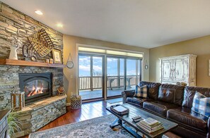 A living room with a stone fireplace, leather sofa, and a view to the outside.