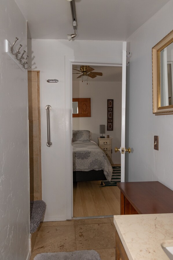 A bedroom with a bed, bedside table, lamp, and a ceiling fan.