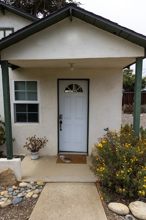 A house with a white door, a small porch, and a window.