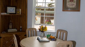 Un comedor con una mesa redonda, cuatro sillas, un armario de madera y una ventana con vistas al exterior.