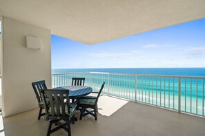 Enjoy the ocean view from this balcony with a table and chairs.