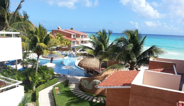 A resort with a swimming pool, palm trees, and a view of the ocean.
