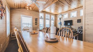 Un intérieur en bois avec une longue table à manger, des chaises et un téléviseur fixé au mur.