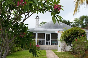 Surrounded by lush greenery, this single-story home features a pitched roof and a charming chimney.