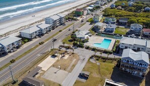 Vista aérea de una zona residencial costera con casas, una piscina y una playa.