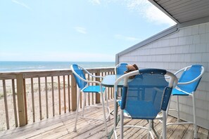 Una terraza de madera con vista a la playa y al océano.