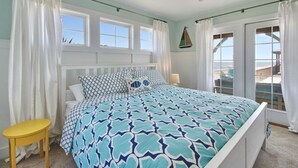 Una camera da letto con un letto, una ventola a soffitto, una finestra e vista all'esterno.