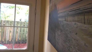 Una habitación con un ventanal grande, una puerta y un cuadro en la pared.