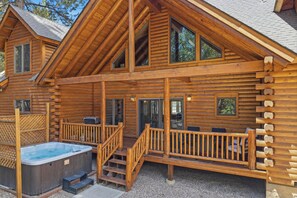 Une cabane en rondins dotée d’un bain à remous, d’un espace salon extérieur et d’une terrasse couverte.