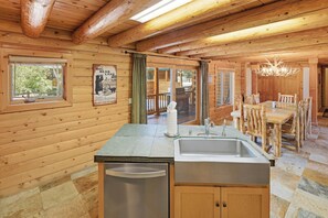 Een houten blokhut interieur met een keukenhoek, inclusief een spoelbak, een afdruiprek en een houten tafel met stoelen.