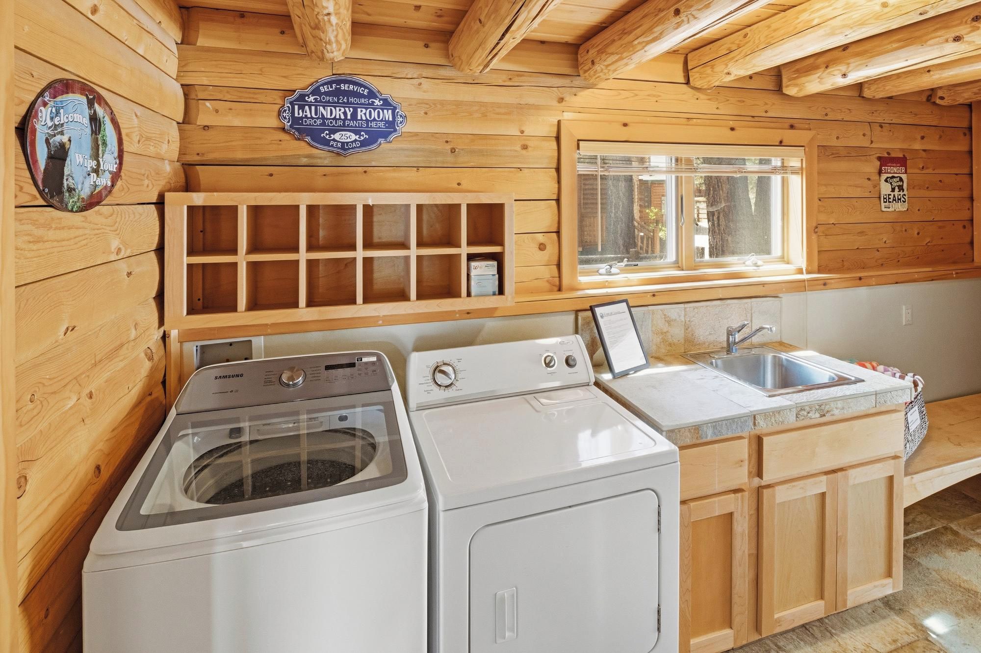 A laundry room with two washing machines, a sink, and a window.