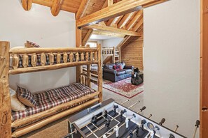 Een gezellig loft slaapkamer met een stapelbed, een slaapbank en een tafelvoetbaltafel.