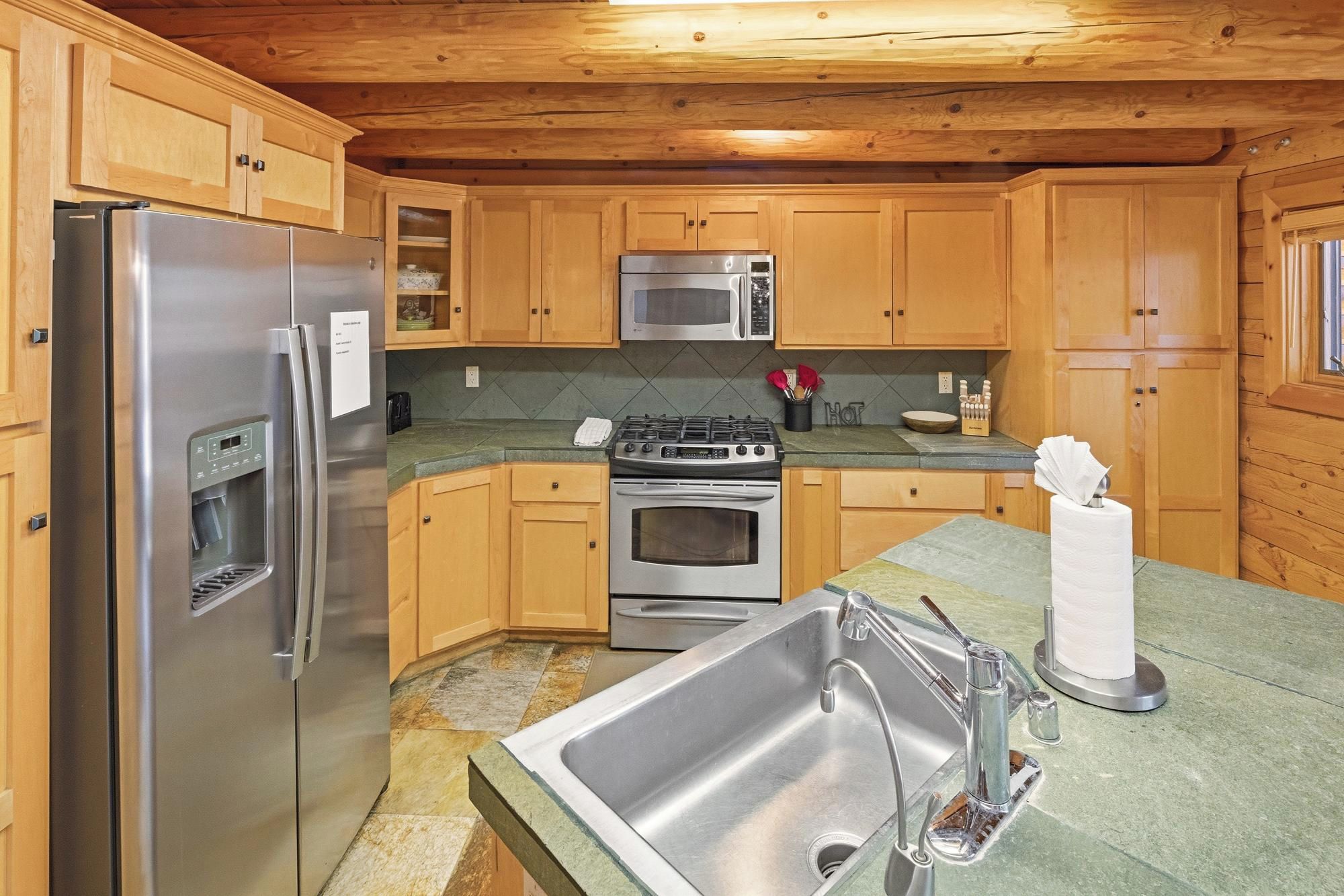 A modern kitchen with stainless steel appliances, wooden cabinets, and a granite countertop.