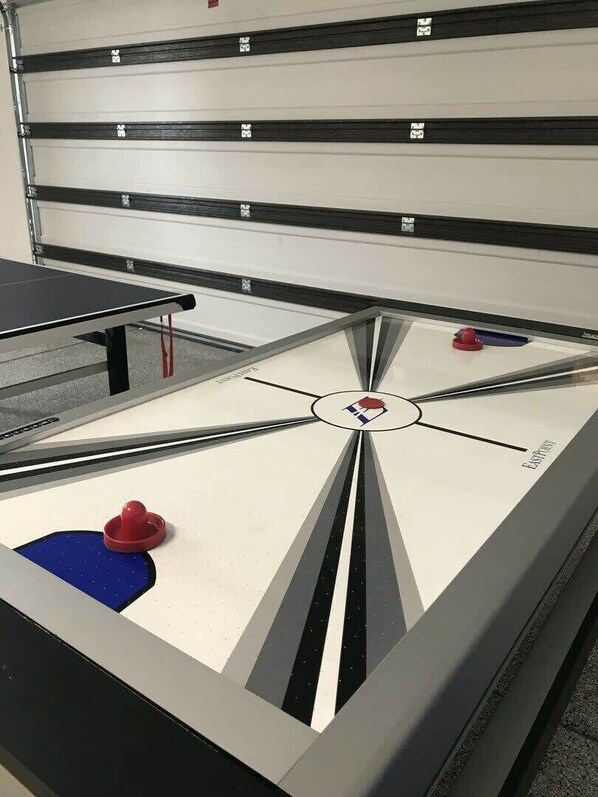 A shuffleboard table with a logo in the center, a red puck, and a blue puck.