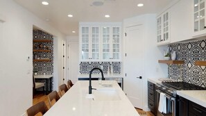 A modern kitchen with a central island, white cabinetry, and patterned backsplash.