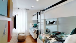 Ein modernes Schlafzimmer mit Etagenbetten, einer kleinen Sitzecke und Bildern an den Wänden.