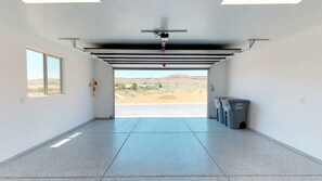 Eine Garage mit freiem Ausblick, einem Fenster links und zwei Müllbehältern rechts.