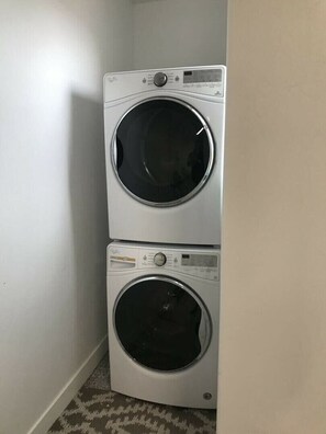 Eine übereinander gestellte Waschmaschine und ein Trockner in einer Ecke des Raumes.