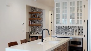 A modern kitchen with white cabinetry, a patterned backsplash, and a built-in oven.