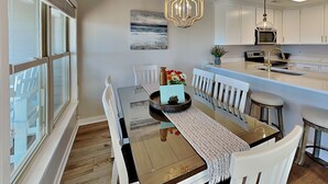A modern kitchen with white cabinetry, a central island, and a chandelier. - Serenity Now | Community Beach Access + Pool! (Topsail Beach)