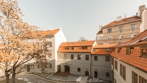 A courtyard with a brick pathway, a tree, and buildings with red-tiled roofs. - Doppler's Apartment fully A/C (Prague)