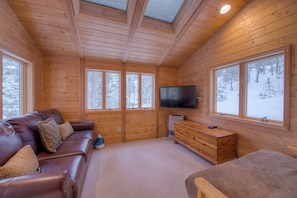 Relax in a spacious room with a high ceiling, skylight, and comfortable leather sofa.