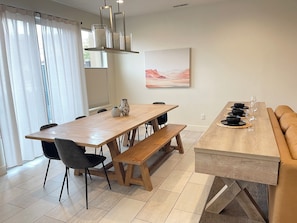 A dining area with a wooden table, chairs, benches, and a sofa.