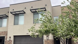 A modern two-story building with a garage, stone accents, and a tree in front. - Entrada 606-Moab Adventure Basecamp (Moab)