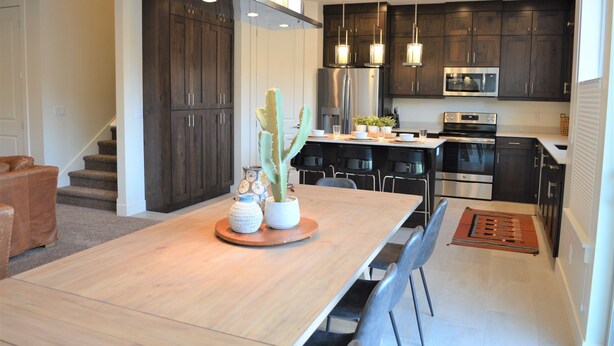 A modern kitchen with dark wood cabinets, stainless steel appliances, and pendant lighting. - Entrada 606-Moab Adventure Basecamp (Moab)
