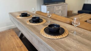 A dining table with black bowls and woven placemats, a television in the background, and a sofa in the living area. - Entrada 606-Moab Adventure Basecamp (Moab)