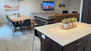A modern kitchen with a dining area, a TV, and a large window. - Entrada 606-Moab Adventure Basecamp (Moab)